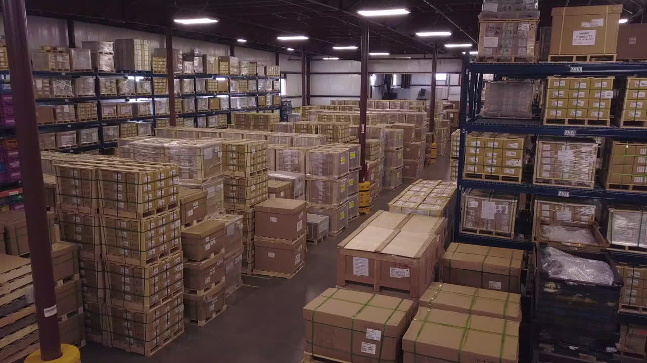 Aerial of boxes stacked on floor and shelves in industrial warehouse