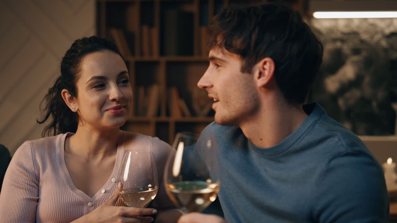 부부는 집에서 만적인 저녁을 즐기고, 커플은 와인과 함께 소파에 앉아 있습니다.