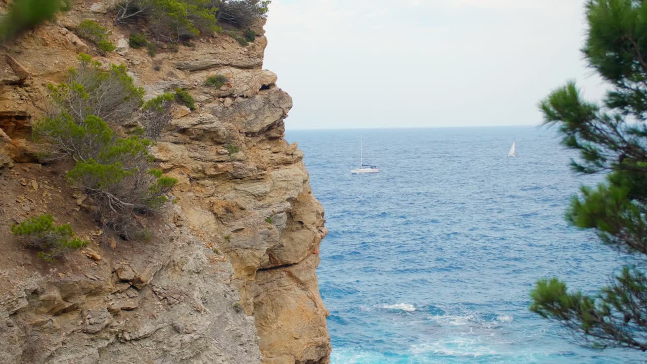 acantilados rocosos y hermoso mar azul visto desde el camino costero con un barco que pasa