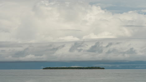 thick cumulus clouds blow over tiny island off new caledonia