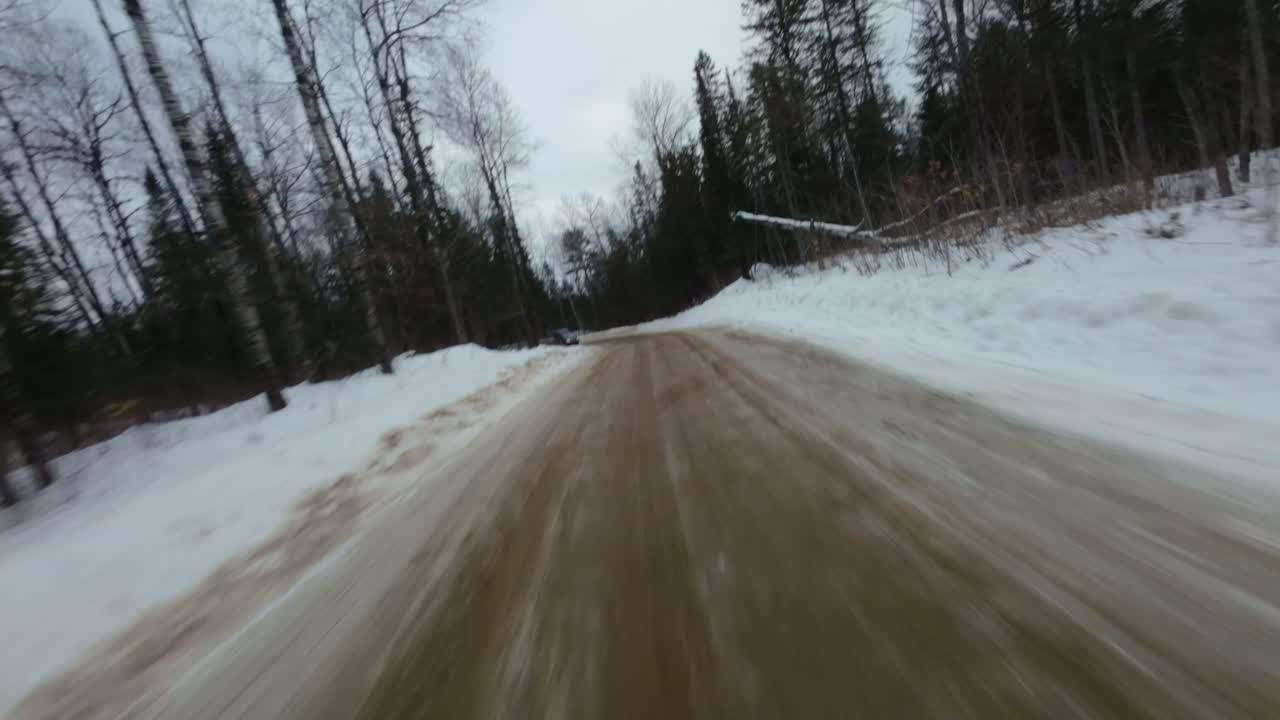 Driving on a Snowy Dirt Road through a Winter Forest