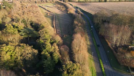 Bury-St-Edmunds-Mostrando-Caminos-Que-Se-Curvan-Entre-árboles-Otoñales,-Automóviles-Y-Campos-En-La-Hora-Dorada,-Vista-Aérea