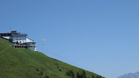 hang glider, gracefully soar through the air passing behind resort building