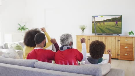 african american family watching tv with diverse male soccer players playing match on screen