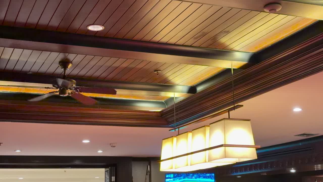 Ceiling fan spins above warm pendant lights in upscale hotel bar, steady camera, ambient lighting