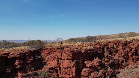 vista lateral de una persona caminando por el borde de una montaña en una aventura de senderismo, el desierto de australia