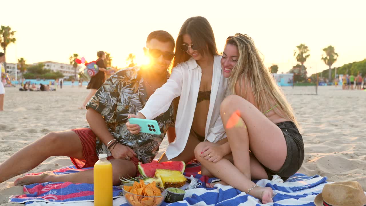 Friends enjoying a beach picnic at sunset