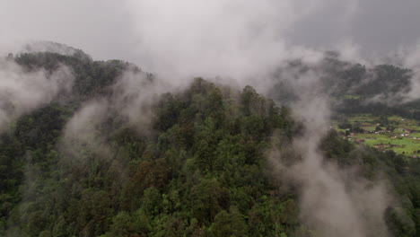 Aerial-Orbit-of-a-mountain-with-trees-and-cloud-cover-in-Valle-De-Bravo,-Mexico