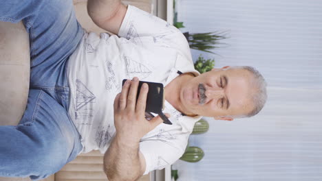 Vertical-video-of-Old-man-laughing-at-phone-message.