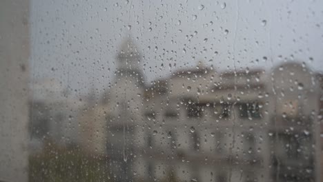 Una-Vista-Cercana-En-Cámara-Lenta-De-Fuertes-Lluvias-Mientras-Las-Gotas-De-Lluvia-Caen-Sobre-El-Vidrio-De-Una-Ventana