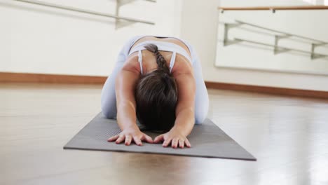 mujer caucásica enfocada practicando yoga en el gimnasio, cámara lenta
