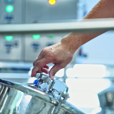 milk factory indoors. worker opens metal mixer for milk. bowl for mixing milk and water. preparing sour cream and cheese. cheese production process. close-up.