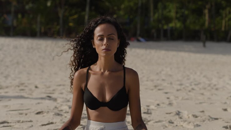Mujer joven meditando en la playa