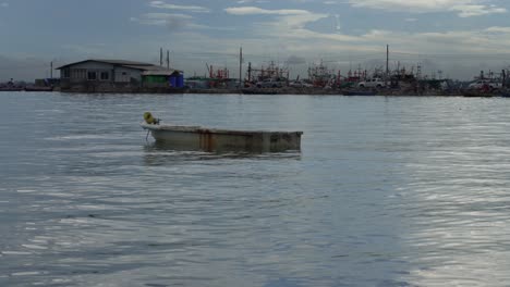 serene view of a small fishing boat against the background of a house is anchored near na kluea fishing boat pier, pattaya, thailand