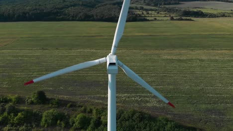 aerial drone shot around single wind turbine generator in grass field