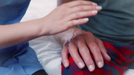 Close-Up-Of-Nurse-Comforting-Senior-Man-On-Home-Visit