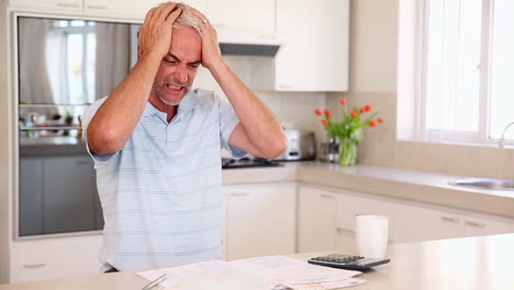 Stressed-man-working-out-finances-at-the-counter