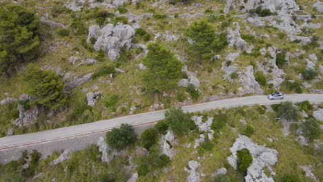 Largo-Tiro-Panorámico-Lateral-Siguiendo-Coche-Peugeot-208-Por-Carretera-Sinuosa-En-Calobra,-Mallorca,-España