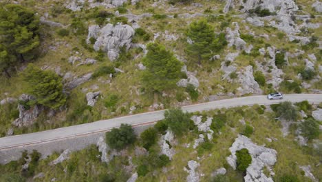 largo tiro panorámico lateral siguiendo coche peugeot 208 por carretera sinuosa en sa calobra, mallorca, españa