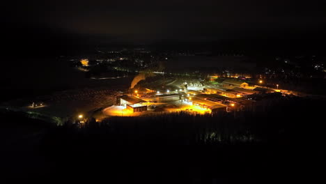 aerial view around a large wood processing factory, winter night in finland