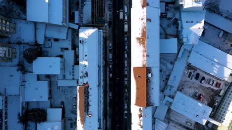 aerial top down view of beautiful city center with red tile roofs, street and traffic covered in snow during winter in stuttgart, germany