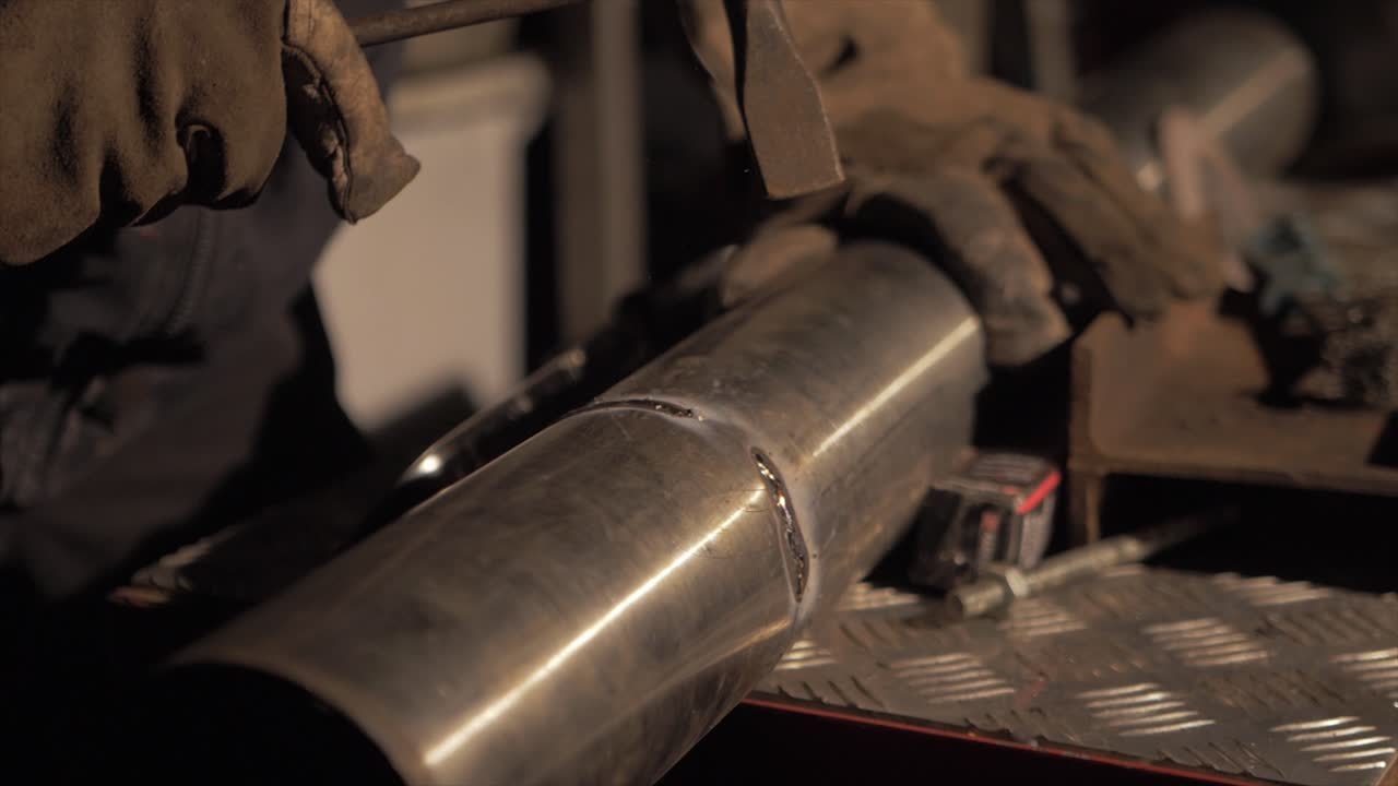 망치로 과도한 용접 플럭스를 끊는 용접기