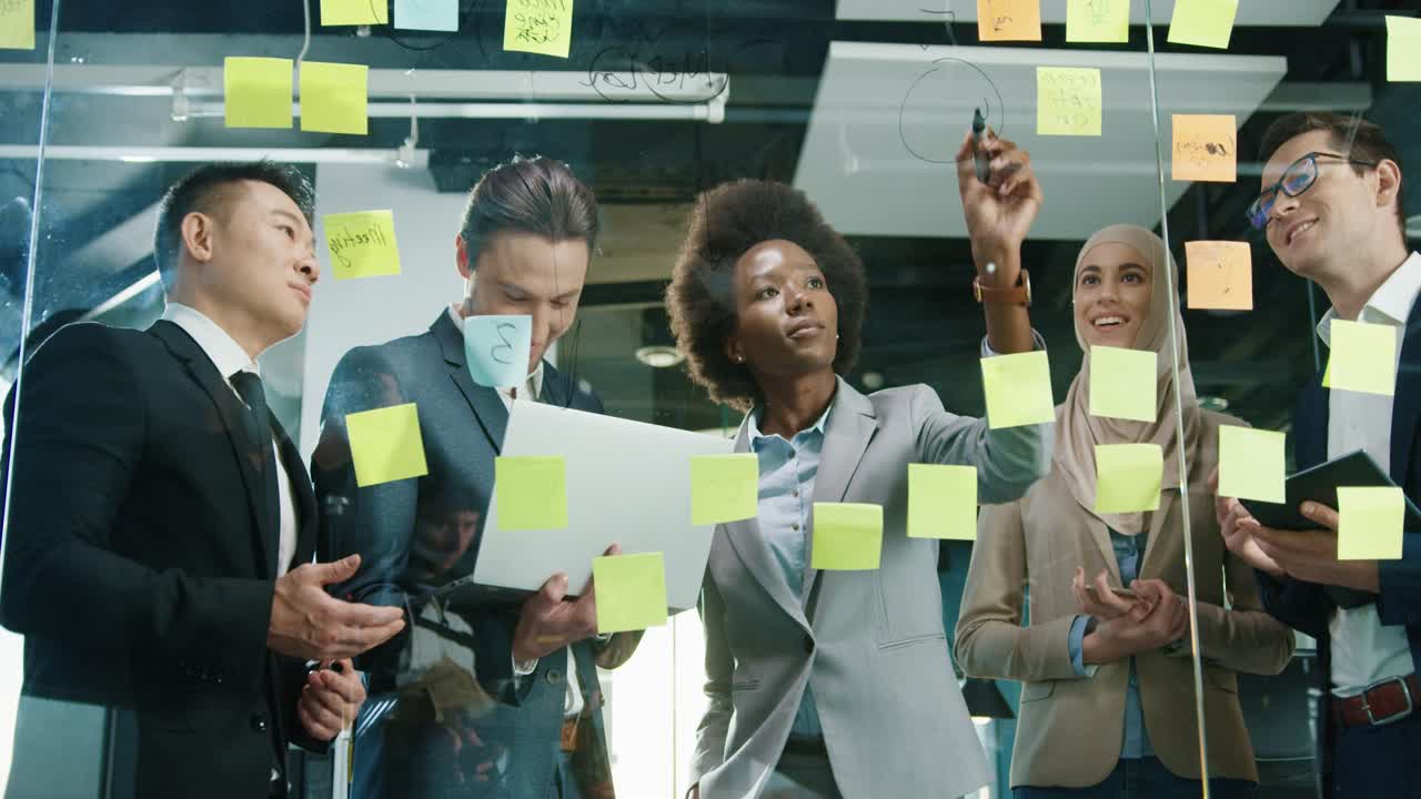 Top View Of Multiethnic Business People Group Working In A Modern Office While Writing On Glass In A Cabinet With Sticky Notes