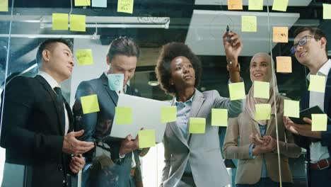 visão superior do grupo de empresários multiétnicos trabalhando em um escritório moderno enquanto escreve no vidro em um armário com notas autoadesivas