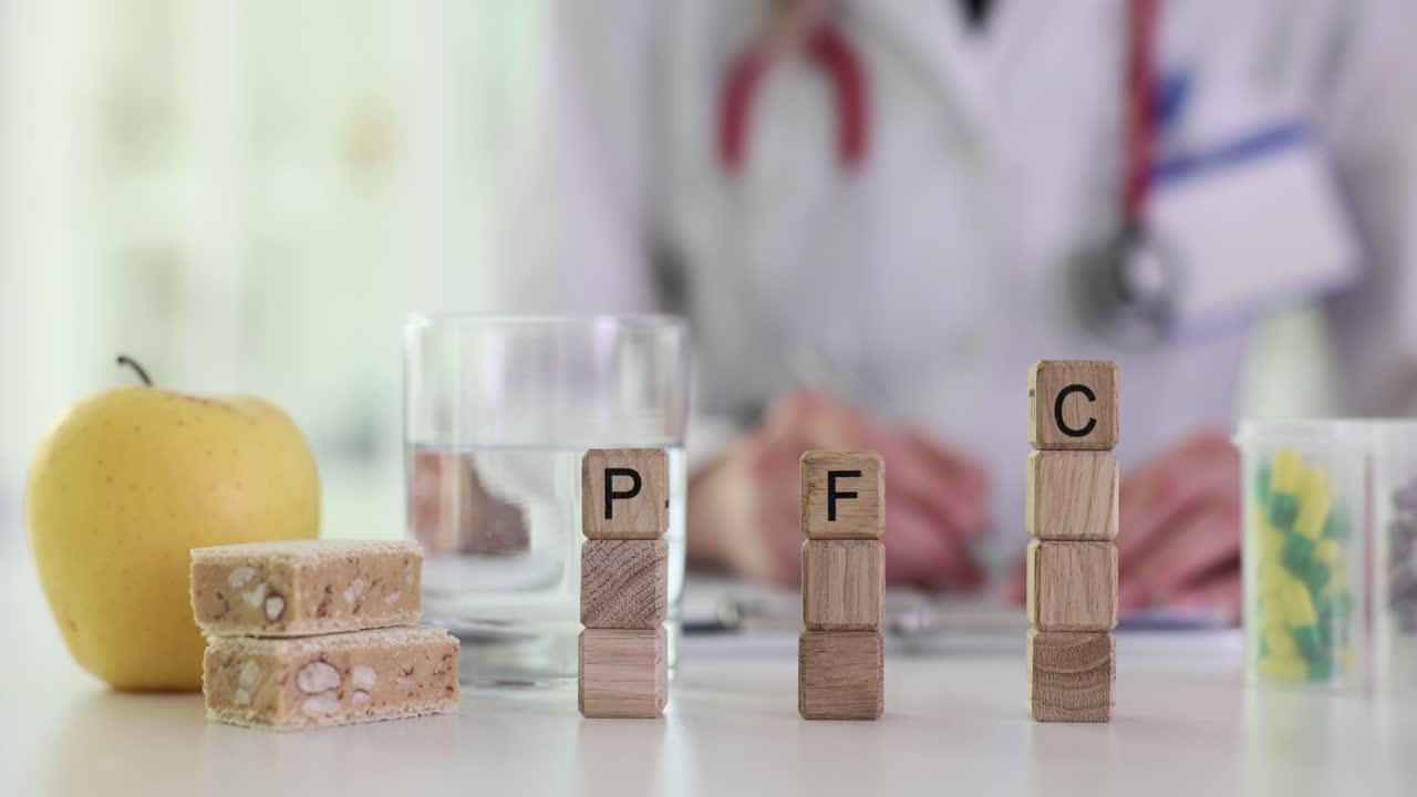 Balok kayu menunjukkan huruf pfc di dekat pil dan apel oleh dokter.