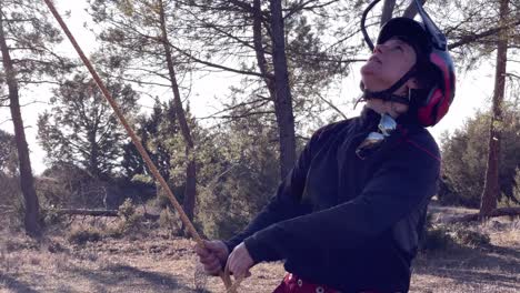 mujer sacude la cuerda atada a un árbol mientras poda árboles en un bosque de pinos en españa
