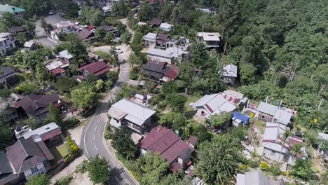 indian village with road snaking through, surrounded by lush vegetation of tropical forest, drone footage