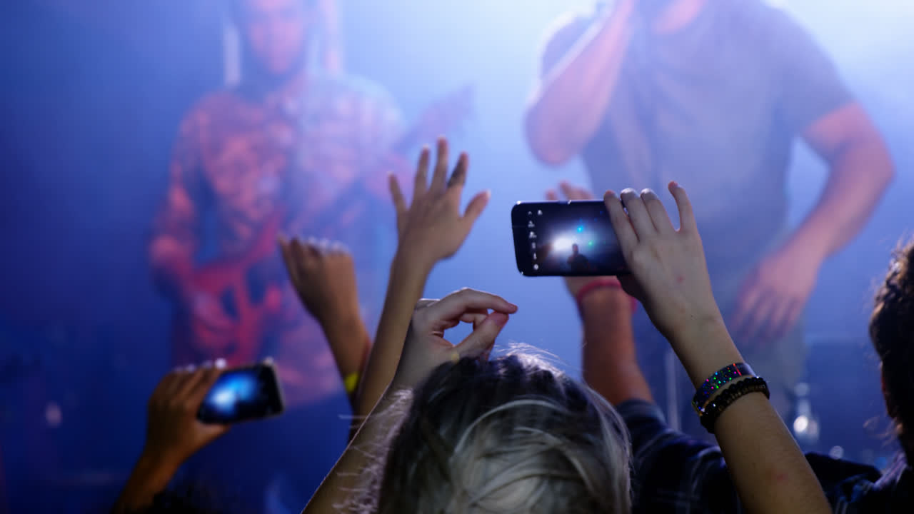 Audience recording video of musical band on mobile phone 4k