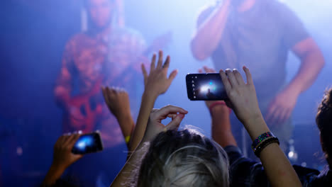 audience recording video of musical band on mobile phone 4k