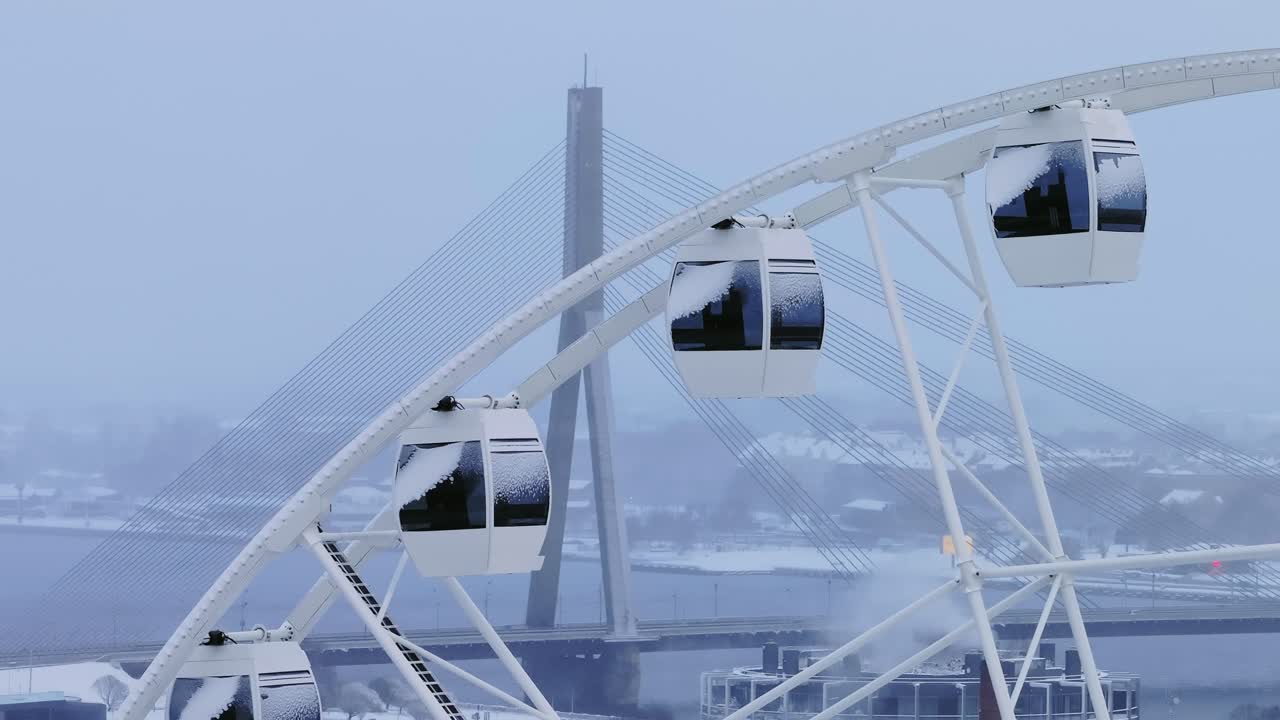 White Ferris wheel, iconic Vanšu Bridge of drone, overcast winter day, Riga, 4K