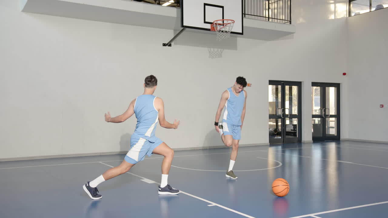 Basketball players stretching on court, preparing for practice session indoors