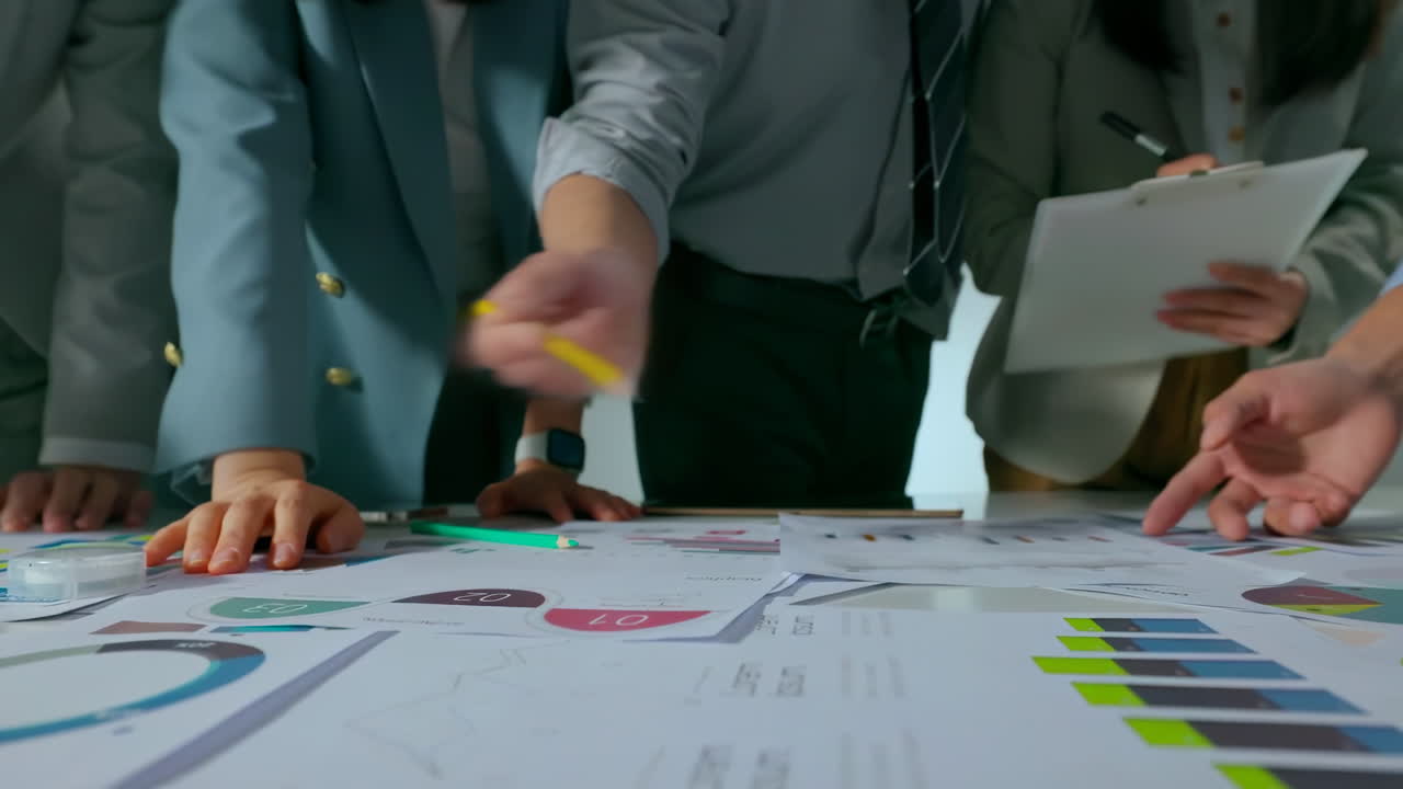 Teamwork and Collaboration Professionals Brainstorming in a bright, modern office, with laptops, financial charts, and creative materials on the table