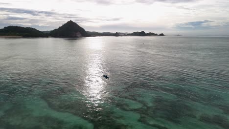 low ocean flyover: outrigger canoe passes through sun beam on water
