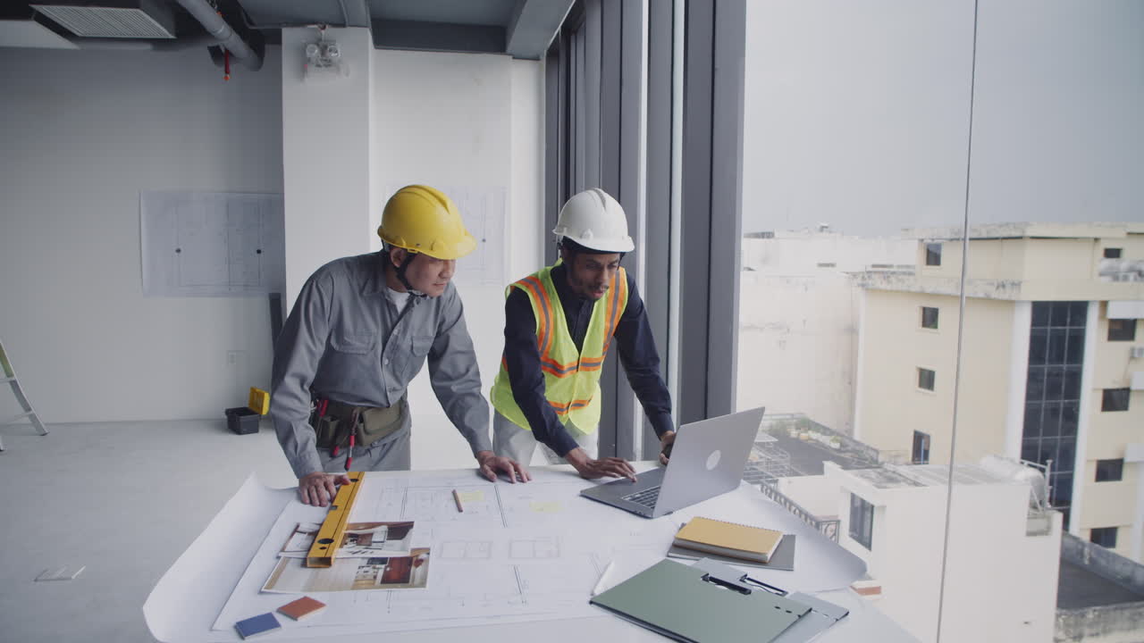 Male Engineers Checking Workplan near Table with Blueprints