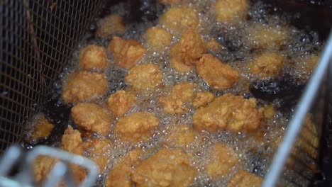 delicious crunchy and crispy karaage chicken, korean fried chicken cooking in progress, deep frying in boiling hot oil fast food commercial kitchen, night market pub food, close up shot