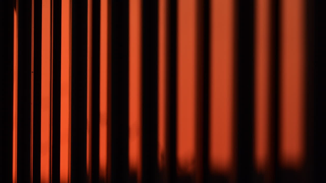 Unique vertical lines creating beautiful orange patterns in urban light during sunset. window reflection