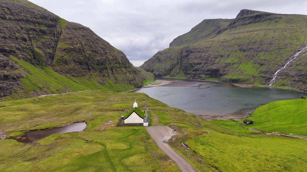 Cinematic aerial view of a dramatic fjord with towering cliffs, black sand river delta, and Atlantic horizon in the Faroe Islands, highlighting raw Nordic wilderness beauty