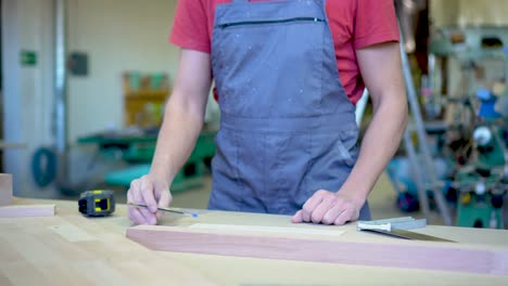carpenter measuring and marking wood in a workshop