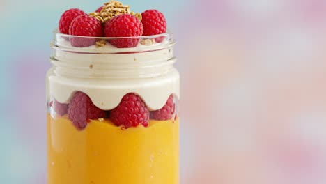 delicious layered dessert in a jar featuring creamy vanilla whipped topping, bright mango layer, and fresh raspberries for a refreshing treat