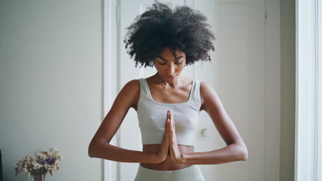 une fille paisible pratiquant le yoga en intérieur. une femme africaine méditant le namaste.