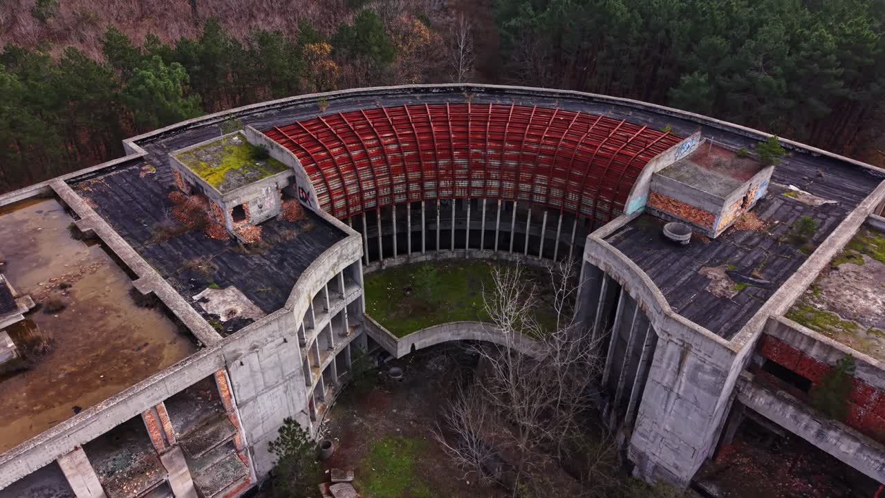 Aerial view of a circular abandoned structure with rusted roof