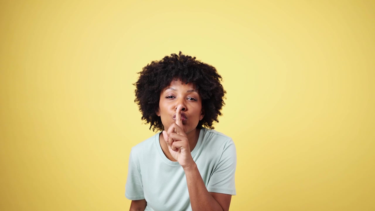 Giovane donna afroamericana che chiede silenzio con il dito sulle labbra