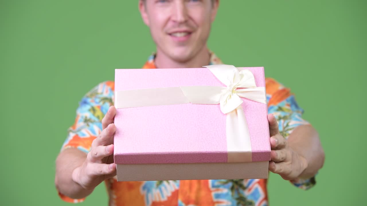 Young handsome tourist man giving gift box