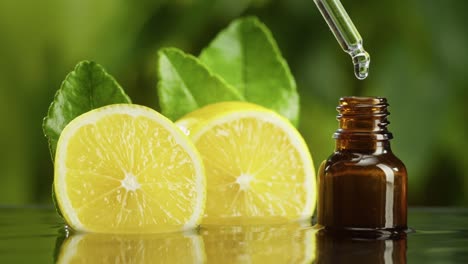 dripping lemon juice from pipette into bottle close-up, vitamin oil. making aroma serum on green background. dropping liquid citrus extract, skincare routine, treatment spa. traditional medicine