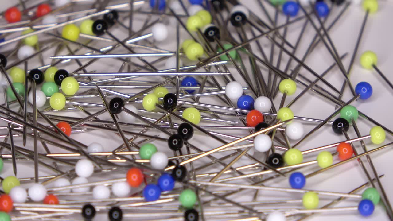 회전하는 색 배경에 다채로운 유리 머리를 가진 많은 핀의 루프 영상을 촬영할 수 있습니다.