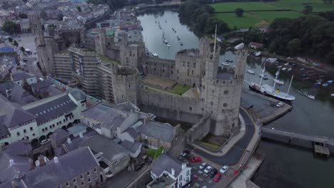 Alte-Caernarfon-Burg-Walisische-Hafenstadt-Luftaufnahme-Mittelalterliches-Wahrzeichen-Am-Wasser-Von-Oben-Nach-Unten-Rechts-Umlaufbahn